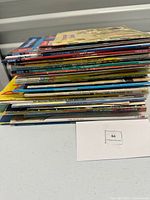 Stack of over 50 colorful children's books with visible spines, showing varied titles and publishers