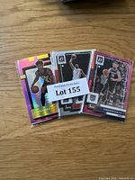 Three NBA basketball cards featuring Ochai Agbaji, Domantas Sabonis, and another player. Cards are sleeved and show colorful designs with holographic effects.