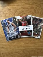 Three NBA basketball cards in protective sleeves including Luka Dončić 'My House' and Christian Wood cards