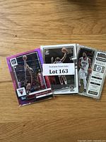Front view of a selection of basketball cards showcasing Nikola Vucevic and a Joel Embiid card designed like a season ticket, with some cards in protective sleeves.