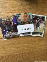 Photo showing three basketball trading cards with action shots of players and the lot number card