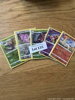 Top view of 5 Pokémon cards in yellow sleeves revealing some Pokémon characters.