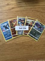 Five Pokémon cards fanned out on a wooden surface showing Lumineon, Sudowoodo, Ferrothorn, and Gible cards with a lot label