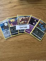 Five Pokémon cards fanned out on wooden surface including Panic Mask, Crobat, Krookodile, Gastly, and an unidentified purple Pokémon card.