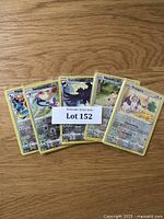 Photo of five Pokémon cards including Porygon2, Ambipom, Corviknight, Meowth, and Snorlax, displayed with a lot label on a wooden surface.