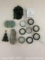 Lot overview showing 5 pendants and 9 green to light lavender carved bangles arranged on a white surface.