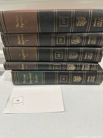 Stacked view of five leatherette hardcovers showing volume numbers 16-20 and authors Ptolemy through Thomas Aquinas.