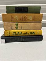 Front view of the stacked books showing spines with clear titles and publishers in varied condition.