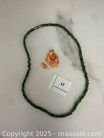 Full view of necklace and pendant with broken petal on white marble surface