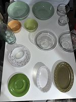 Photo showing mixed bowls, teacup with saucer, dishes, and plates arranged on a white table.