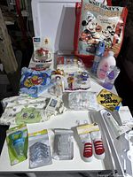 Photo shows various new baby items arranged on a table including clothing, bottles, teethers, and baby care items.