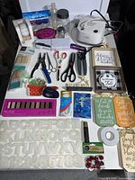 Full view of miscellaneous household and craft items spread out on table.