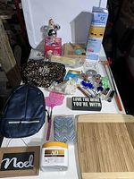 Photo of assorted miscellaneous items on a white surface including backpacks, Christmas decor, keyrings, kitchen and personal care items