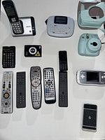 Overview of various electronics including remote controls, cordless phone, calculator, label maker, and instant camera case.