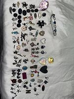 Various charms and bracelet laid out on white fabric, showing assortment of shapes and materials