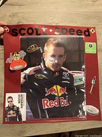 Signed Scott Speed photo mounted on a red background with themed stickers