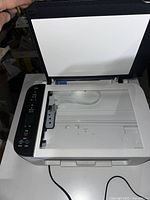 Canon Pixma printer with open scanner lid showing glass scanning surface and control panel on left.