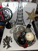 Lot of mixed home decor items including Eiffel Tower figurine, glass vase, starfish sculpture, decorative spheres in a wire basket, and armillary sphere model.