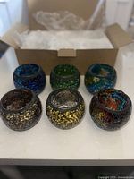Set of 6 round glass candle holders with crackled patterns in blue, green, brown, yellow, and multicolor.
