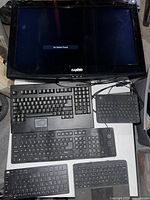 Photo showing Sanyo TV displaying 'No Device Found' message and five keyboards of various types on a surface.