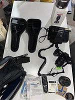 Photo of entire camera equipment lot including Minolta cameras, cases, film cartridges, tripod box, and accessories on a white tabletop.