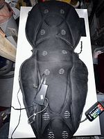 Full view of the black fabric chair massager pad with visible massage node patterns, power cord attached.