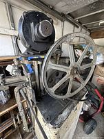 Side view of the vintage Foley Manufacturing saw filer showing the large handwheel and motor assembly.