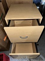 Wooden filing cabinet with two drawers. Top drawer partially open, showing inside.