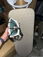 Iron with control knobs and power cord held in hand