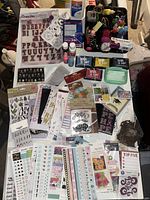 Overview of stickers, ink pads, paint bottles, glue bottle, and various arts and crafts supplies arranged on a surface