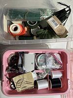 Two plastic containers filled with sewing supplies and floral crafting materials