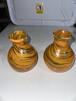 Two small glass vases with swirling brown, orange, and green glass pattern, facing forward.