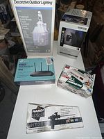 Full lot view showing all items including outdoor light box, TP-Link router box, laminator box, adhesive tool box, and Portfolio LED light box.