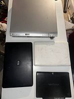 Photo of the Panasonic DVD player, white MacBook, black Dell laptop and black Nextbook tablet shown together on a table.