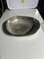 Metal accent bowl viewed from above, showing its irregular organic shape and hammered texture.