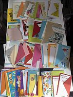 Large assortment of colorful greeting cards and envelopes spread out on a table.