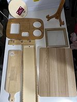 Photo showing various wooden boards arranged on a flat surface along with a wooden easel and a picture frame