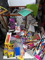 Wide view of the large glass box filled with assorted school and office supplies including visible boxes of Crayola colored pencils and various loose items.