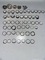 Top view of all 57 vintage rings arranged in rows showing varied sizes and styles, including sparkly, plain, and decorative designs