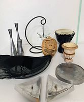 Full view of all items in the lot arranged together on white background including candlesticks, candle holders, djembe drum, coconut monkey, ceramic vase, and black leaf tray.
