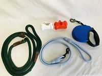 Full view of all leashes and poopie bag holders on white background