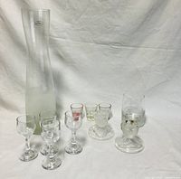 Overview of all glassware items in the lot consisting of a tall vase with label, stemmed glasses, shot glasses and decorative glasses