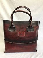 Full front view of hand dyed genuine leather tote bag in brown and dark gradient tones with two small leather handles.