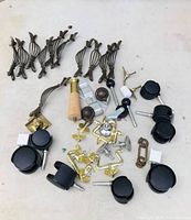 Lot laid out showing decorative metal handles, black caster wheels, wooden-handled tool, brass hardware pieces, and metal brackets