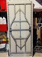 View of plastic foldable table underside showing gray metal support frame and foldable legs