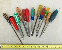 Photo of all 12 assorted screwdrivers showing various handle colors and styles, laid out flat with measuring tape showing lengths.