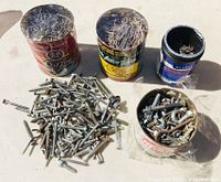 Photo showing four containers filled with assorted screws, nails, hooks, and piles of loose screws and nails on surface