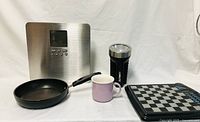 T-fal frying pan, kitchen scale, flashlight, cup, chess set displayed together on white background
