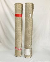 Two beige outdoor patio rugs rolled up vertically against a white backdrop, showing their size and shape.