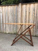 Side view of the wooden ironing board showing the folding leg structure and the elongated ironing surface